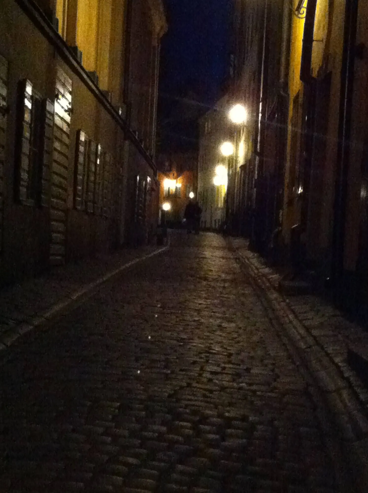 En smal gränd i Gamla stan, upplyst av lyktor en kväll
