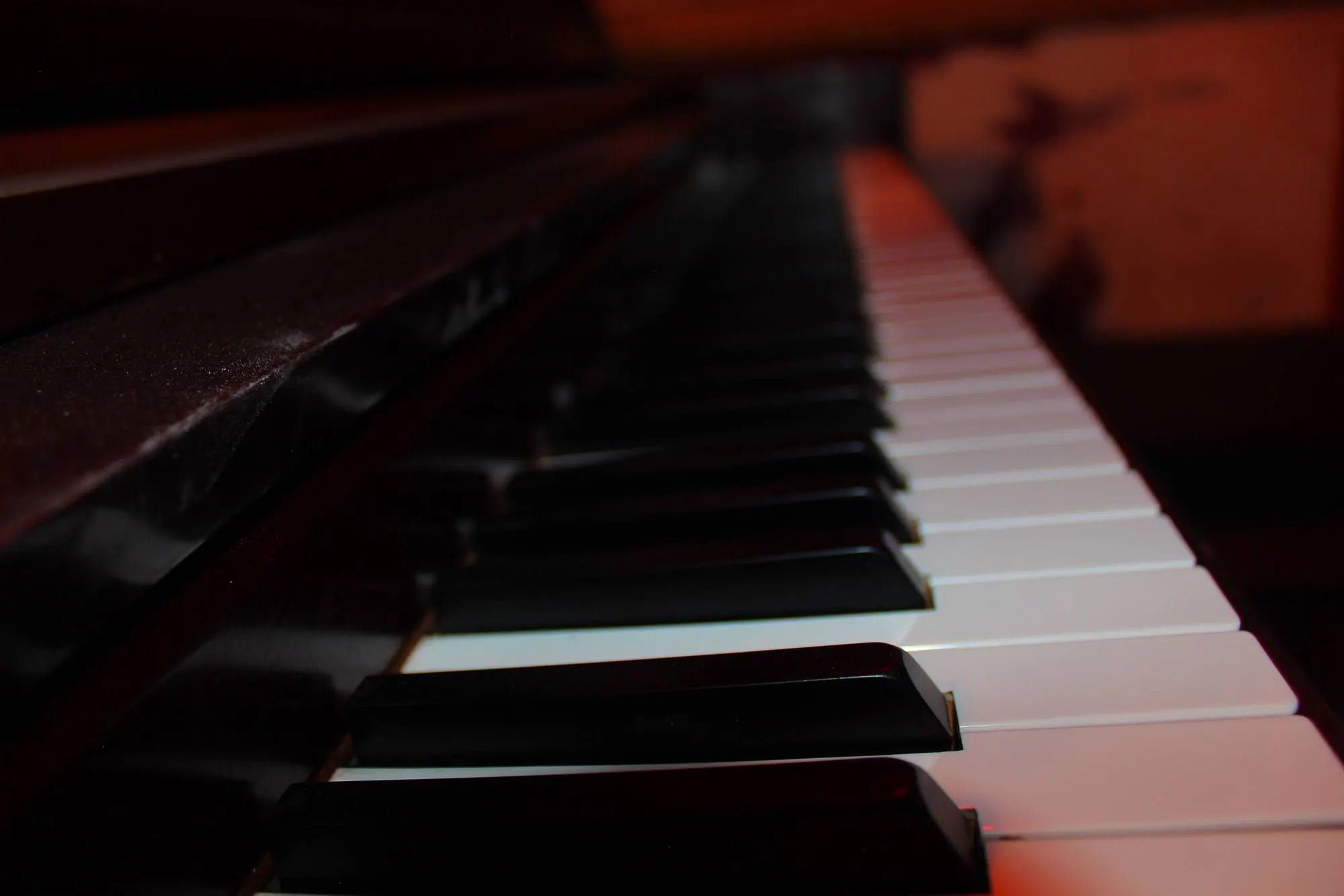 Ett piano i en dunkel bar, i rött ljus